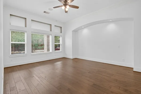 a view of an empty room with wooden floor and a window