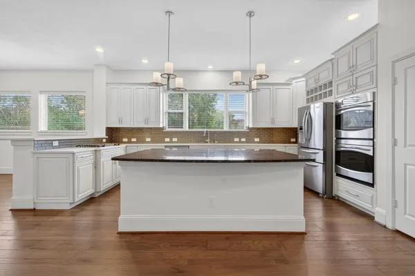 a kitchen with granite countertop a refrigerator a sink and wooden floor