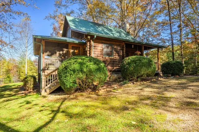 a view of a house with small yard plants and large tree