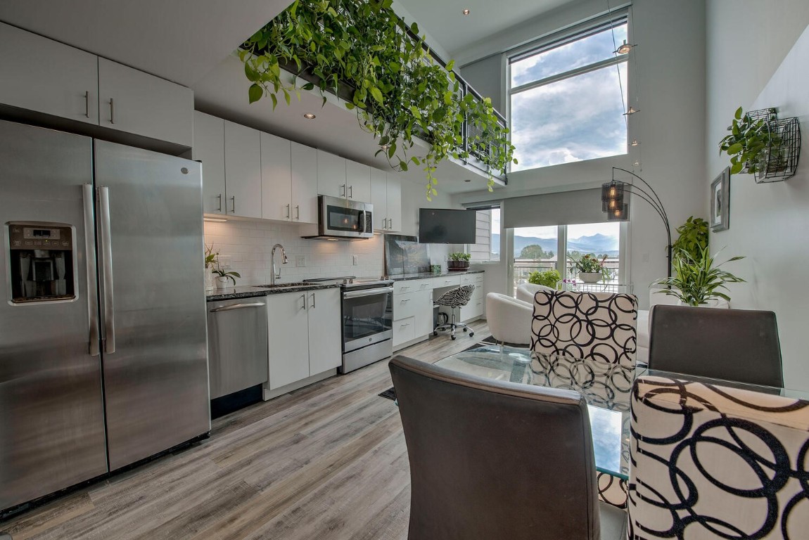 100 Basecamp Way, Unit 217 Frisco, CO 80443 - Photo 8 of 39 a kitchen with stainless steel appliances granite countertop a stove a refrigerator a sink a dining table and chairs with wooden floor