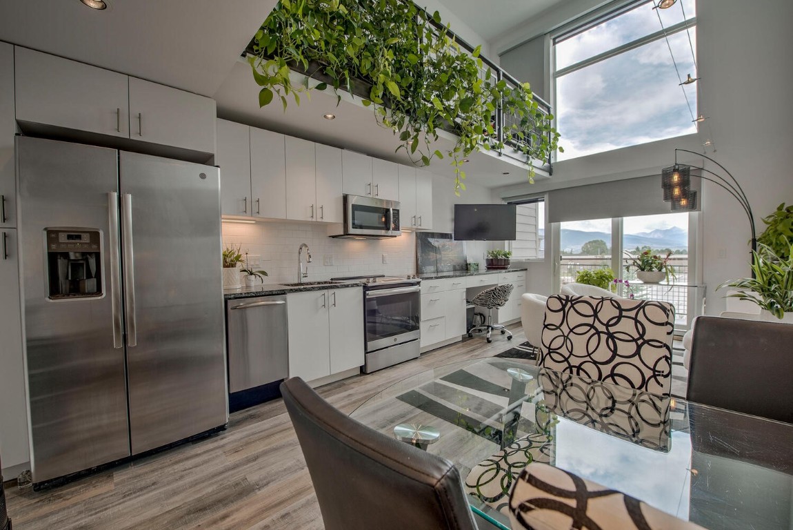 100 Basecamp Way, Unit 217 Frisco, CO 80443 - Photo 10 of 39 a kitchen with stainless steel appliances a refrigerator a sink a stove a dining table and chairs