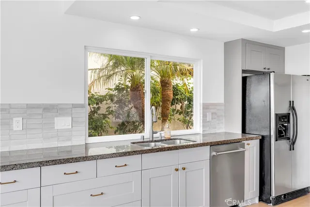 a kitchen with granite countertop a refrigerator and a sink
