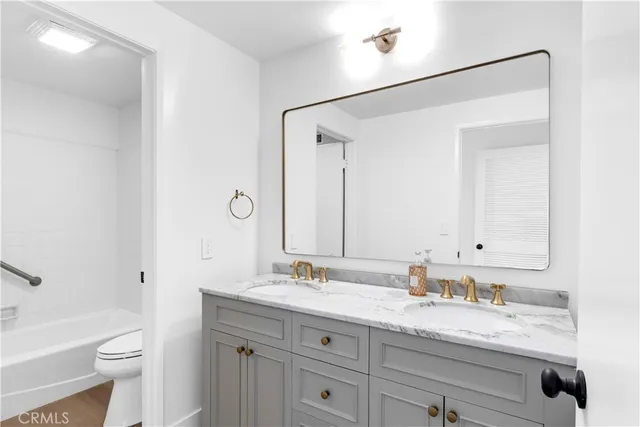 a bathroom with a granite countertop sink a toilet and a mirror