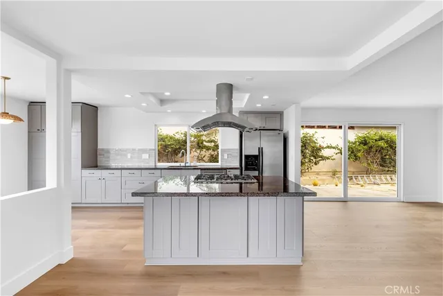 a kitchen with stainless steel appliances granite countertop a stove a sink and a large window with wooden floor