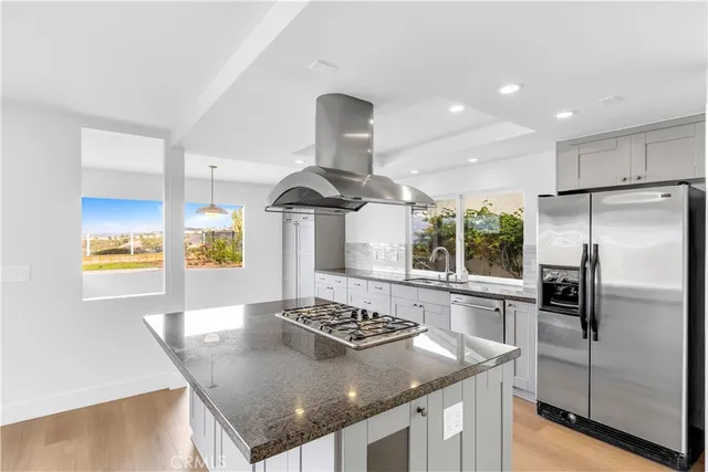 a kitchen with stainless steel appliances granite countertop a sink a stove and a refrigerator