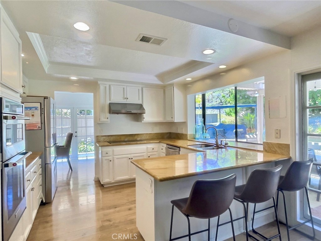 17 Elderberry Irvine, CA 92603 - Photo 6 of 24 a kitchen with stainless steel appliances granite countertop a stove top oven a sink dishwasher a dining table and chairs with wooden floor