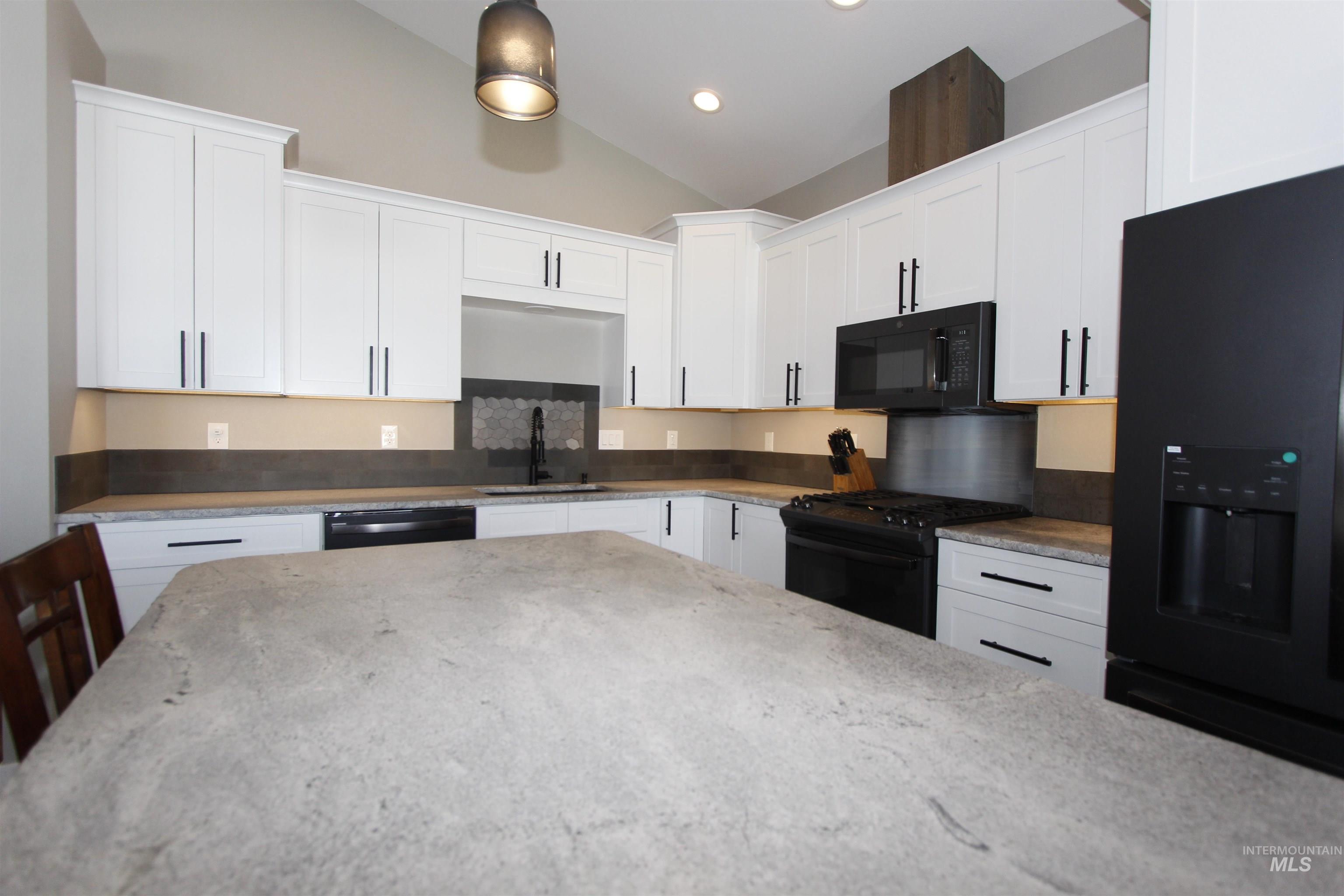 2013 Cedar Avenue Lewiston, ID 83501 - Photo 11 of 46 Kitchen featuring black appliances, white cabinetry, vaulted ceiling, light stone countertops, and recessed lighting