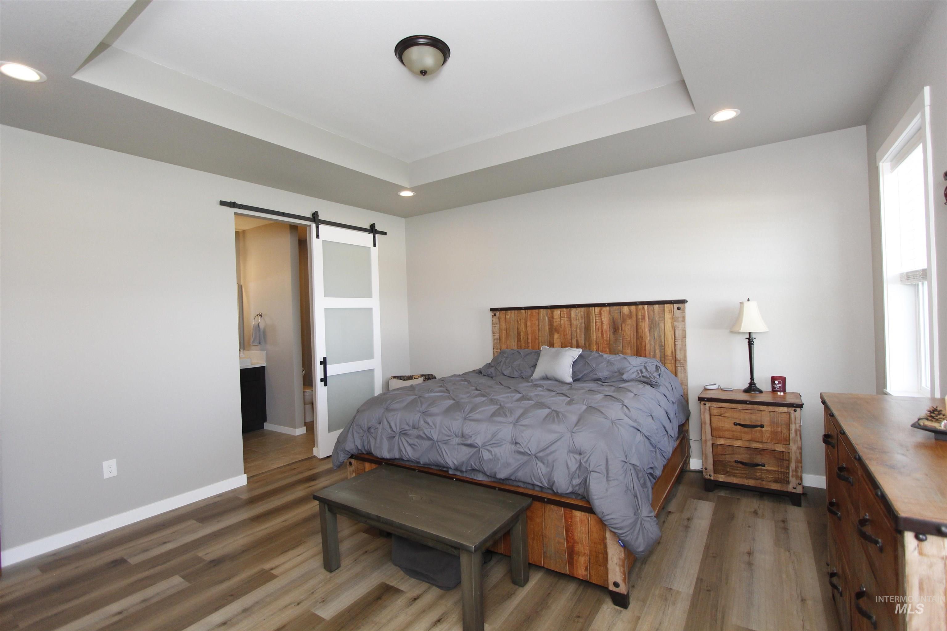 2013 Cedar Avenue Lewiston, ID 83501 - Photo 20 of 46 Bedroom featuring a barn door, recessed lighting, wood finished floors, a raised ceiling, and primary bathroom