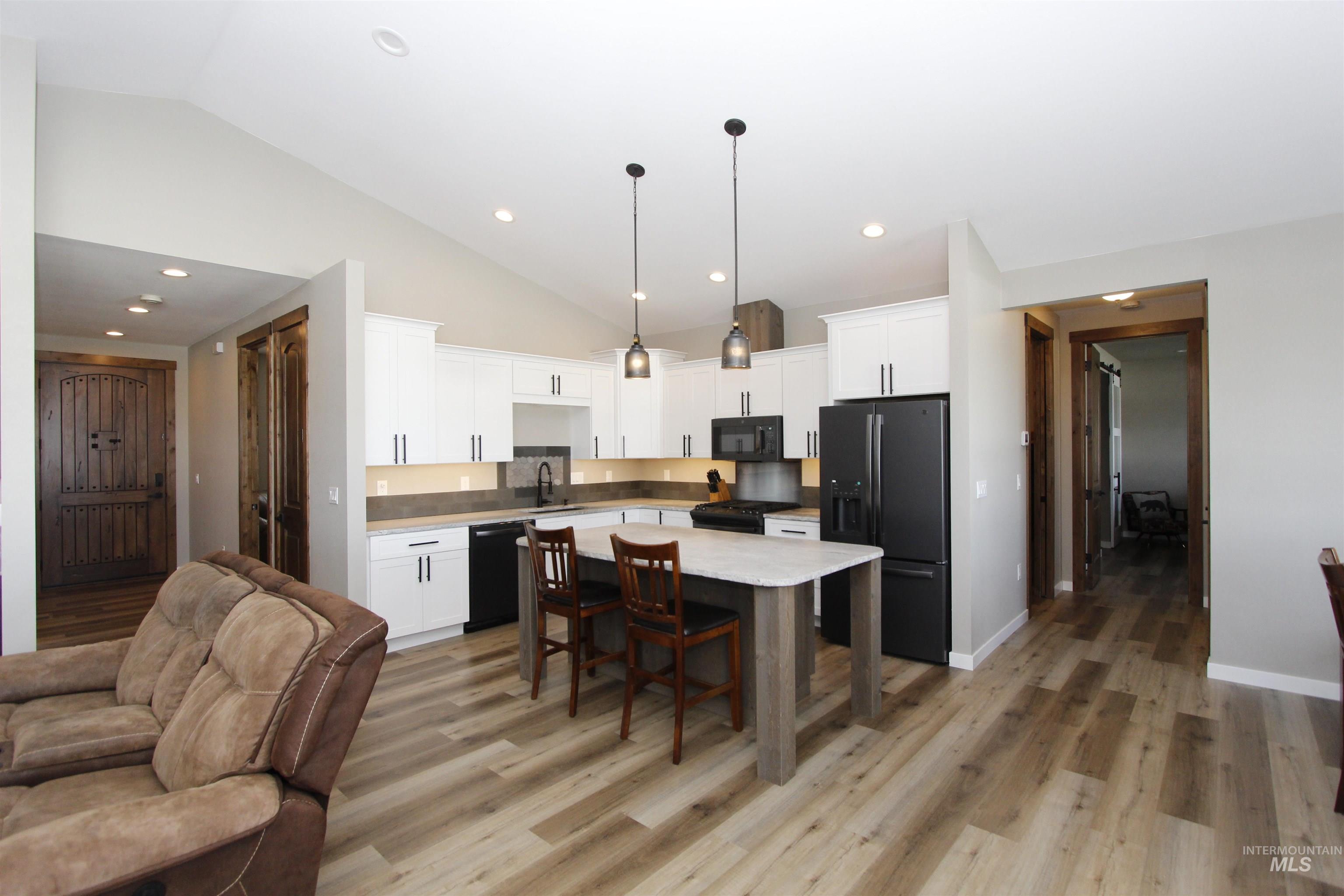 2013 Cedar Avenue Lewiston, ID 83501 - Photo 8 of 46 Kitchen with vaulted ceiling, black appliances, white cabinetry, light wood finished floors, and decorative light fixtures