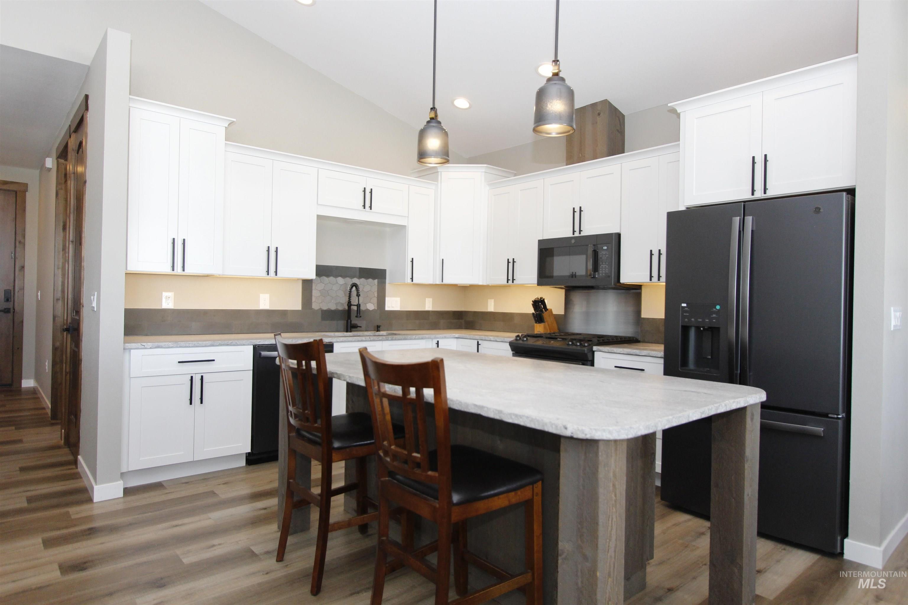 2013 Cedar Avenue Lewiston, ID 83501 - Photo 9 of 46 Kitchen with black appliances, white cabinetry, a kitchen bar, light wood-style floors, and a center island