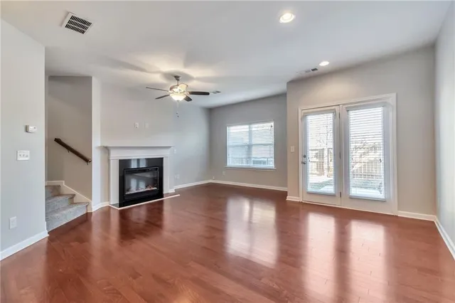 an empty room with wooden floor fireplace and windows