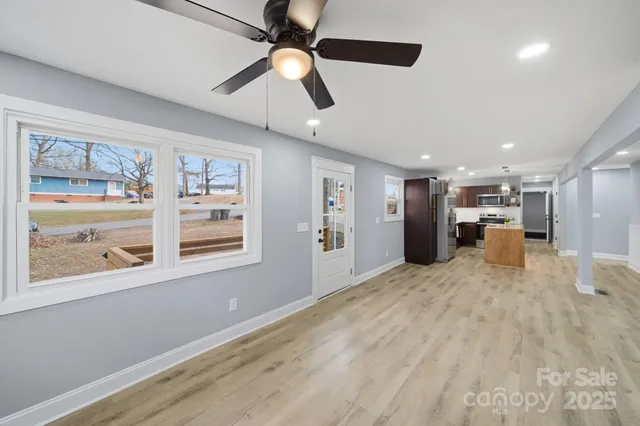 a view of an empty room with a window and a kitchen