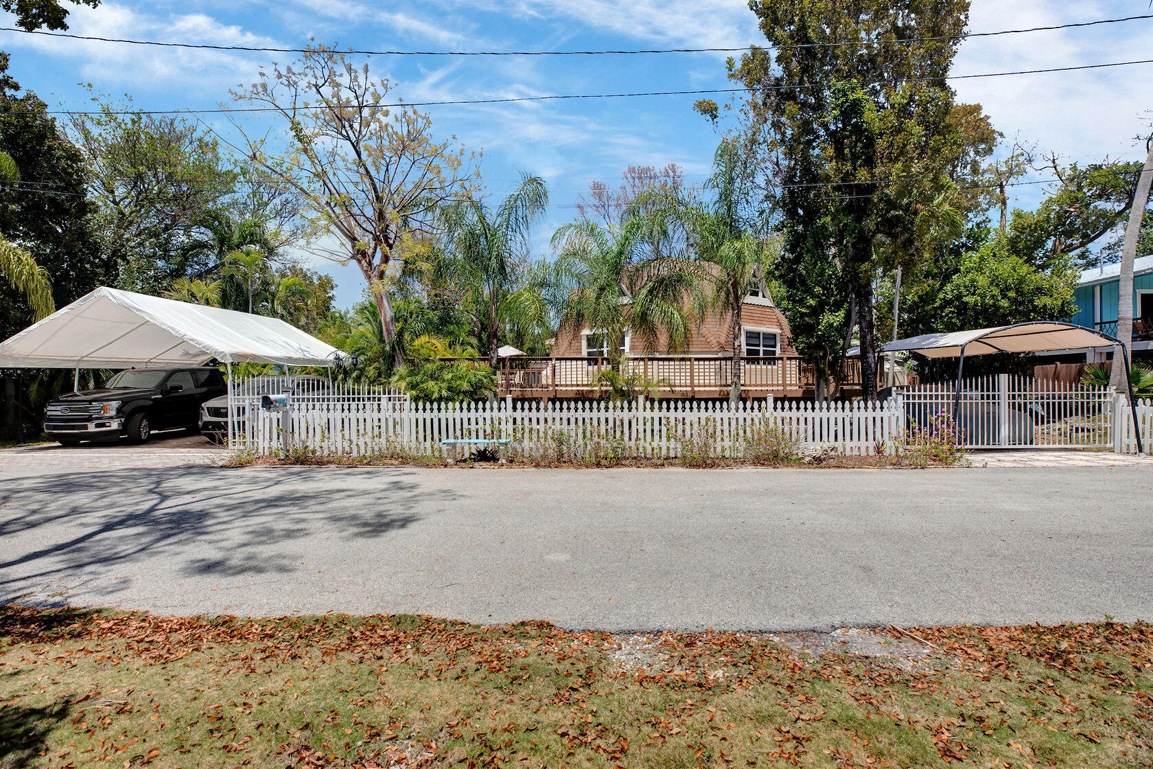 676 Sailfish Trail Key Largo, FL 33037 - Photo 2 of 38 a street view with wooden fence and trees in the background