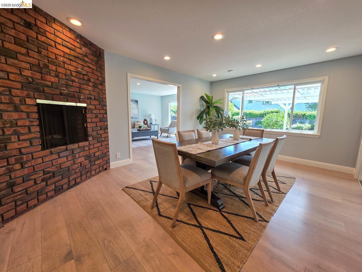 965 Springer Road Los Altos, CA 94024 - Photo 8 of 31 Dining area featuring a brick accent wall with a built-in fireplace, recessed lighting, and wood-finish flooring