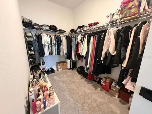 a view of walk in closet with clothes and shoes