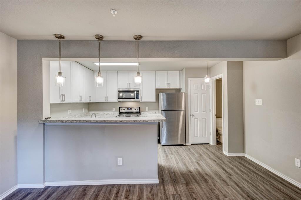 6108 Abrams Road, Unit 503 Dallas, TX 75231 - Photo 18 of 21 a kitchen with stainless steel appliances a refrigerator a sink dishwasher a stove and white cabinets with wooden floor