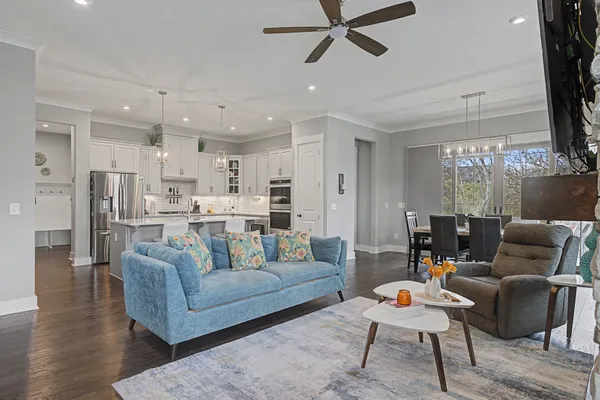 a kitchen with stainless steel appliances kitchen island granite countertop a refrigerator a oven a sink and a dining table with wooden floor