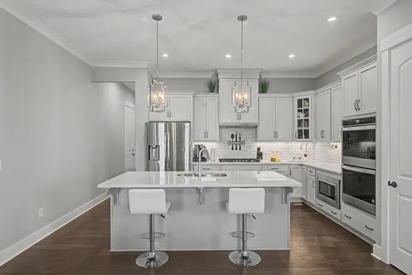 a kitchen with stainless steel appliances granite countertop a stove top oven a sink dishwasher a dining table and chairs with wooden floor