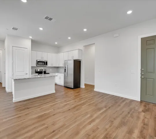 a view of kitchen with kitchen island wooden floor center island and stainless steel appliances