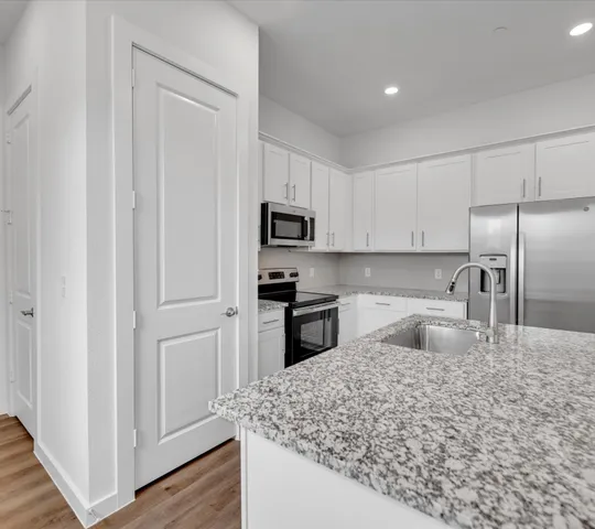 a kitchen with granite countertop a refrigerator sink and microwave