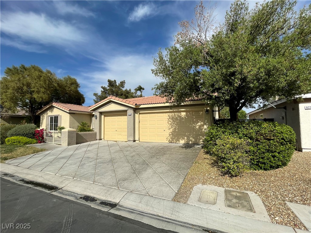 View of front of home featuring a tiled roof, stucco siding, driveway, and a garage