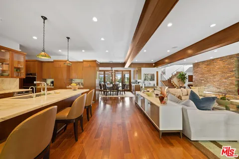 a kitchen with stainless steel appliances a stove a sink a oven a dining table and chairs with wooden floor