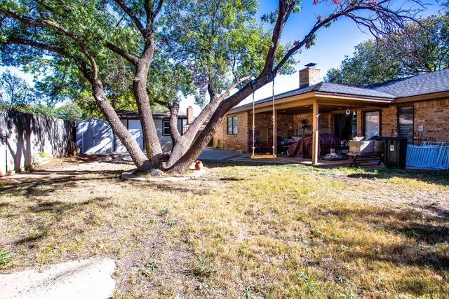 a view of a house with large tree and wooden fence