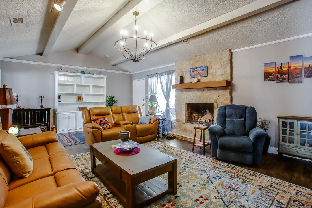 5304 89th Street Lubbock, TX 79424 - Photo 2 of 21 a living room with furniture a fireplace and a chandelier