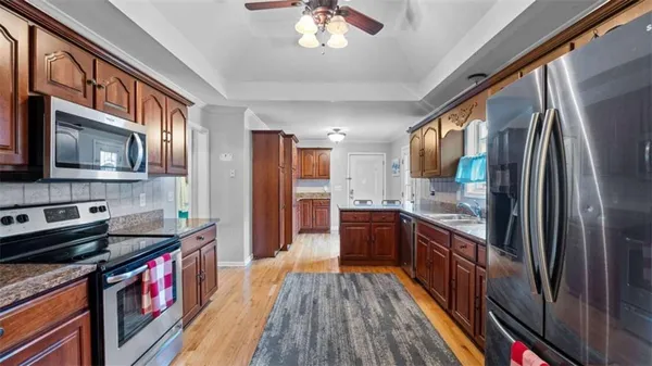 a kitchen with stainless steel appliances granite countertop a stove top oven a refrigerator a sink and dishwasher with wooden cabinets