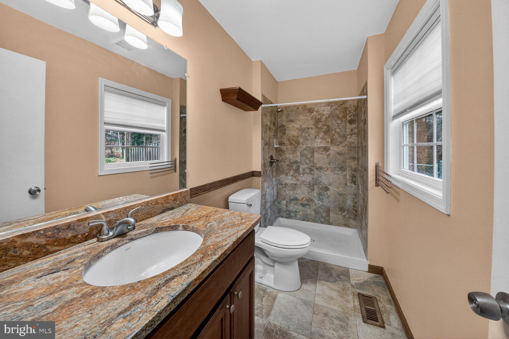 12703 Cedarbrook Lane Laurel, MD 20708 - Photo 20 of 31 a bathroom with a granite countertop sink toilet a mirror a vanity and shower