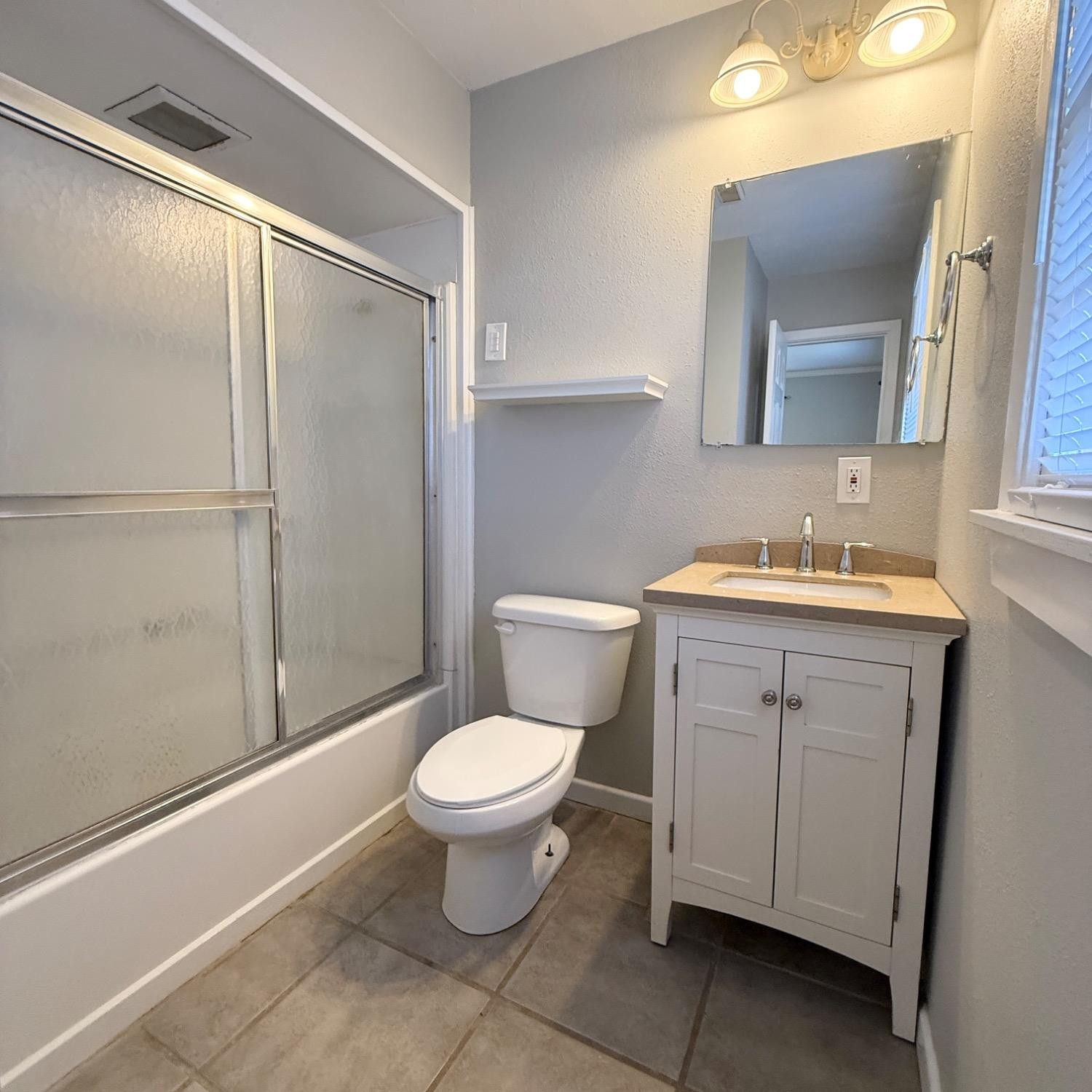 2806 54th Street Lubbock, TX 79413 - Photo 22 of 23 a bathroom with a granite countertop sink toilet and mirror