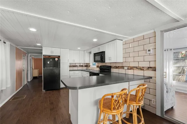 a kitchen with stainless steel appliances granite countertop a refrigerator a stove and a sink with wooden floor