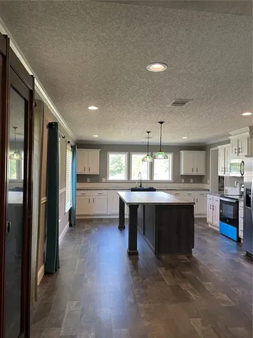 a kitchen with stainless steel appliances granite countertop a refrigerator a sink dishwasher a stove and a dining table with wooden floor