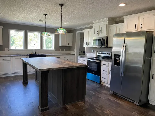 a kitchen with stainless steel appliances granite countertop a table chairs sink refrigerator and microwave