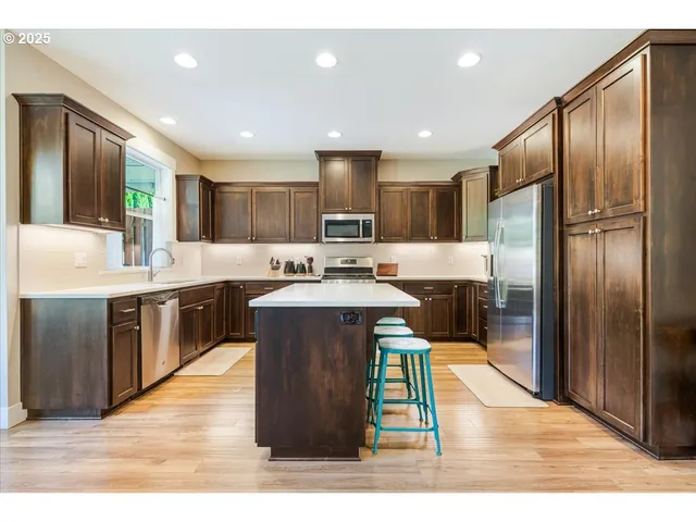 a kitchen with kitchen island granite countertop wooden cabinets a sink a stove a refrigerator and a sink