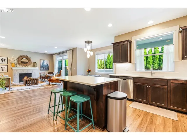 a kitchen with stainless steel appliances granite countertop a stove top oven a sink dishwasher and white cabinets with wooden floor