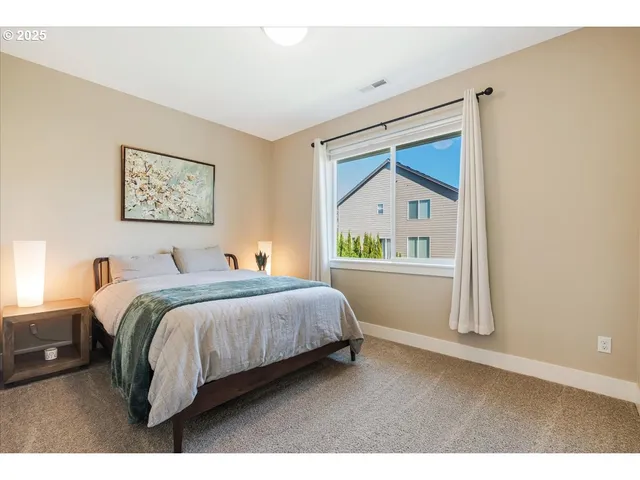 a bedroom with a bed painting on wall and a large window