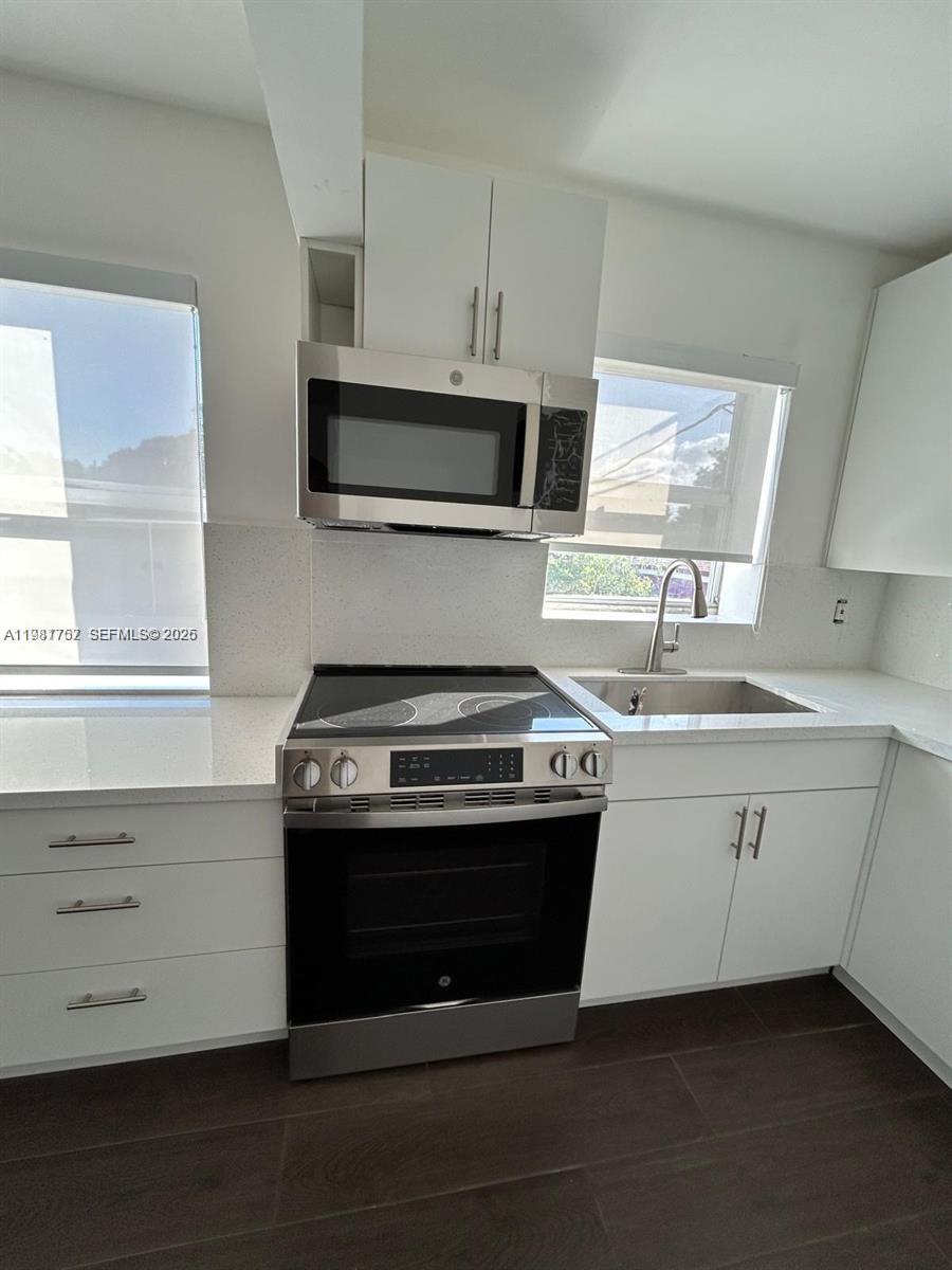 a kitchen with stainless steel appliances a stove sink and microwave