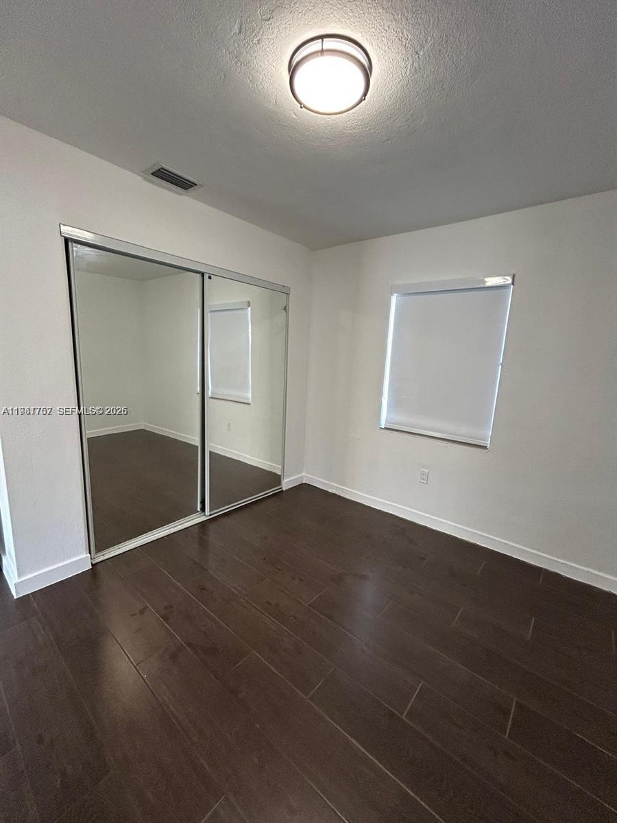 1810 Northwest 34th Street, Unit 2 Miami, FL 33142 - Photo 4 of 11 an empty room with wooden floor and mirror