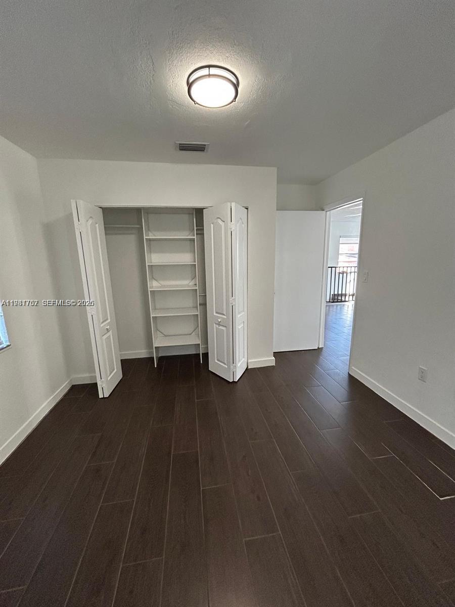 1810 Northwest 34th Street, Unit 2 Miami, FL 33142 - Photo 7 of 11 an empty room with wooden floor closet and windows