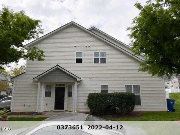 a view of a grey house with a small yard