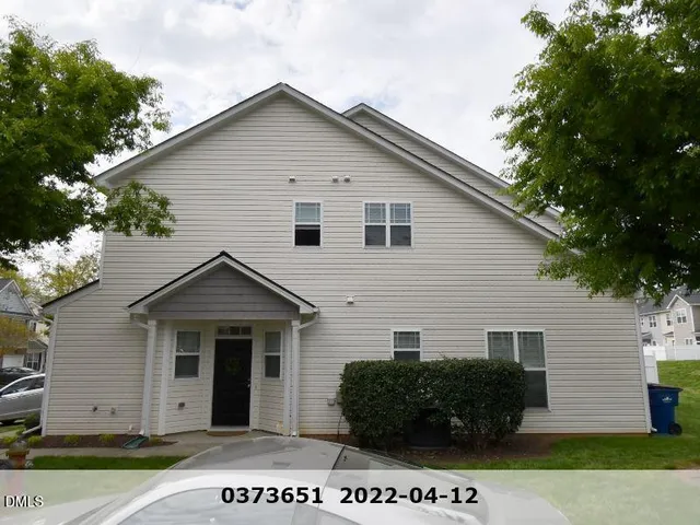 a view of a grey house with a small yard