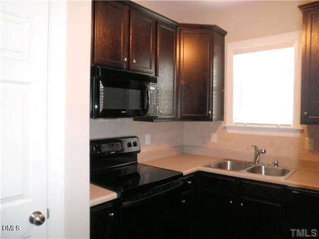 a kitchen with granite countertop a sink stainless steel appliances and cabinets