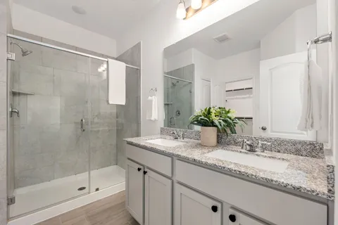 a bathroom with a granite countertop sink a mirror a bathtub and shower