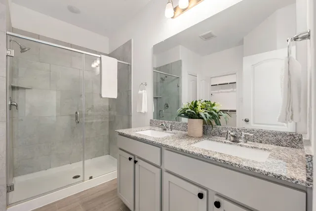 a bathroom with a granite countertop sink a mirror a bathtub and shower