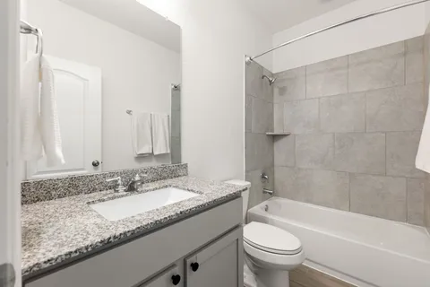 a bathroom with a granite countertop sink a toilet and bathtub