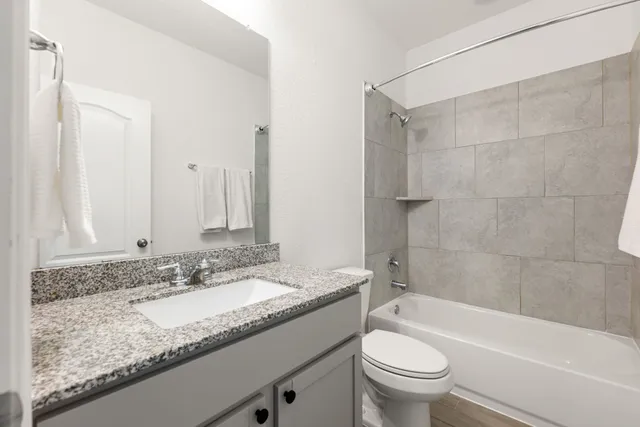 a bathroom with a granite countertop sink a toilet and bathtub