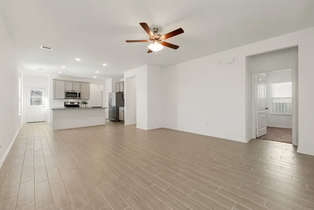 a view of a livingroom with a kitchen island wooden floor and a ceiling fan