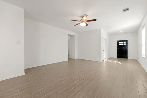 an empty room with wooden floor closet and fan chandelier fan