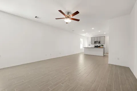 a view of empty room with wooden floor and ceiling fan